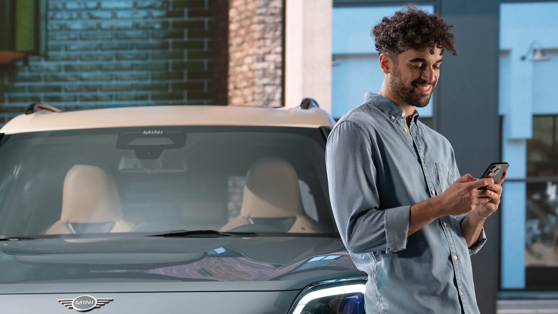 MINI personalizované servisní schůzky - muž stojící vedle MINI píše na telefonu